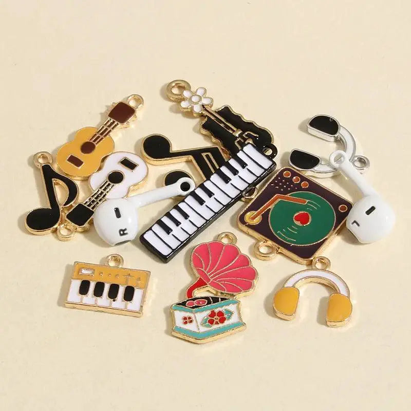 10pcs enamel guitar, keyboard, and music-themed jewelry charms on a beige background