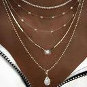 Multiple necklaces with various designs on a person's neck