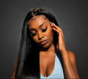 A woman with long, straight black hair wearing a light blue top, posing against a dark gray background.