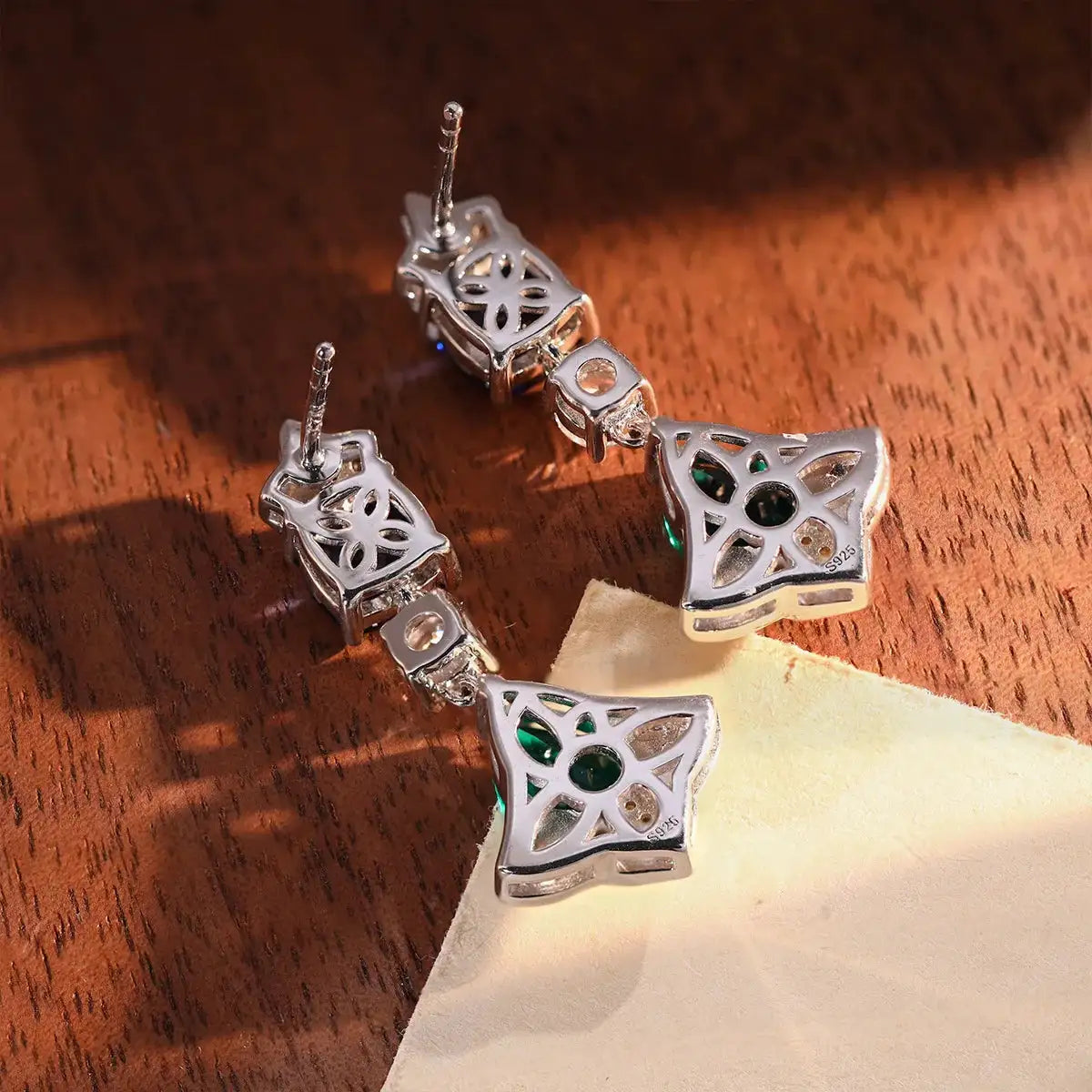 Cluster drop earrings described with sapphire and emerald accents