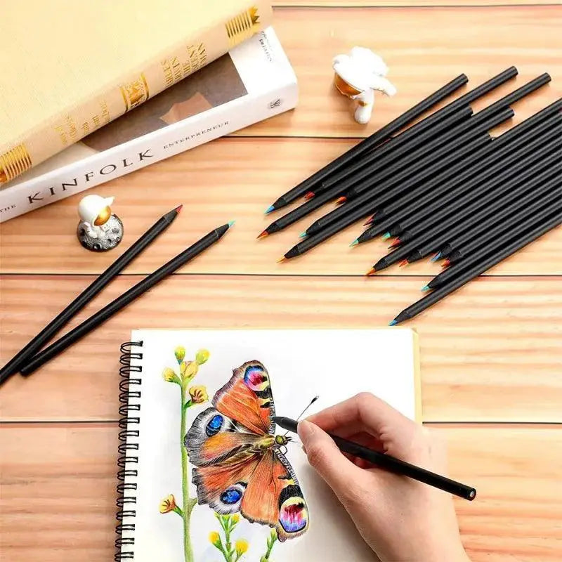 Hand drawing butterfly with colored pencils on sketchbook, art supplies on wooden desk, OurLum.com