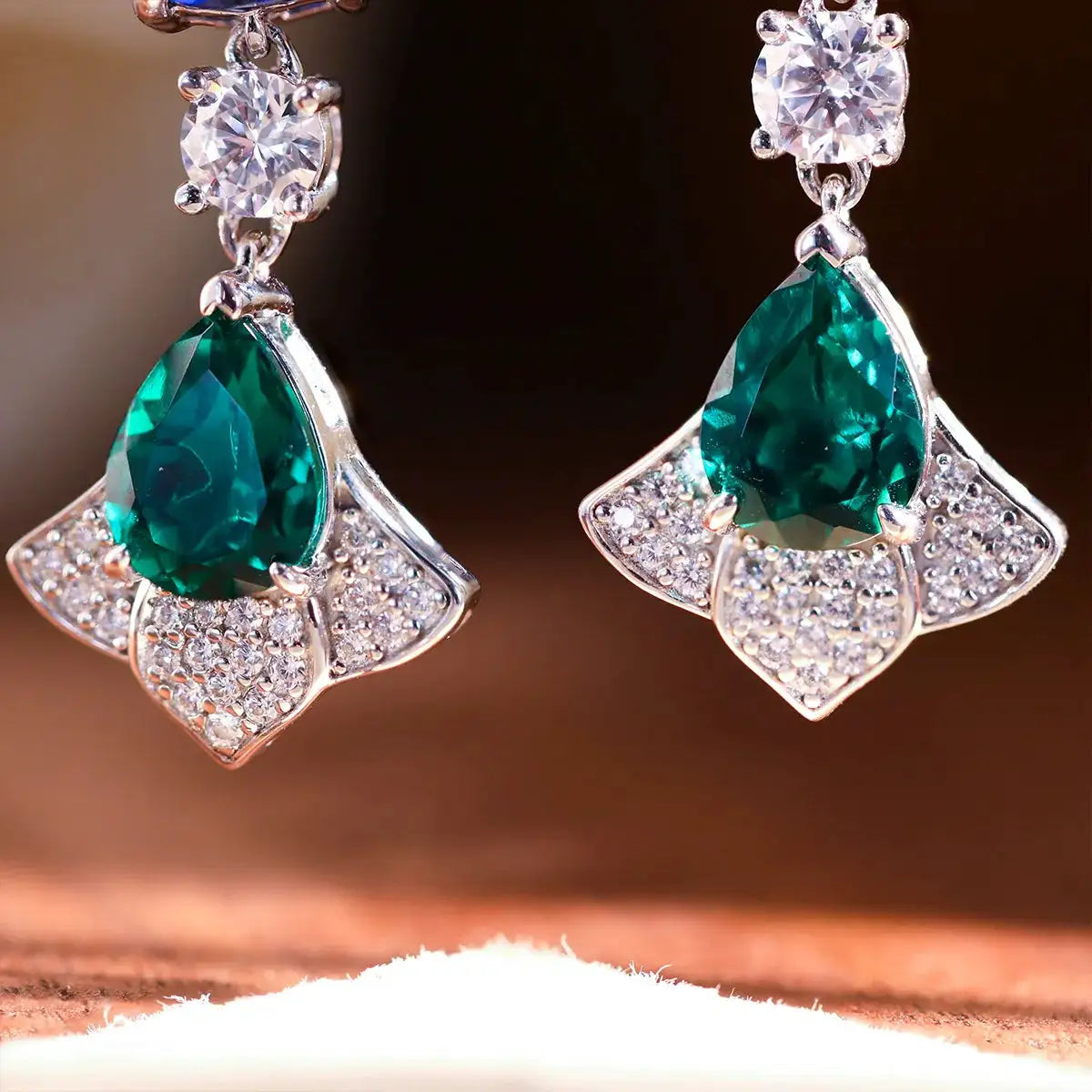 Cluster drop earrings described with sapphire and emerald accents