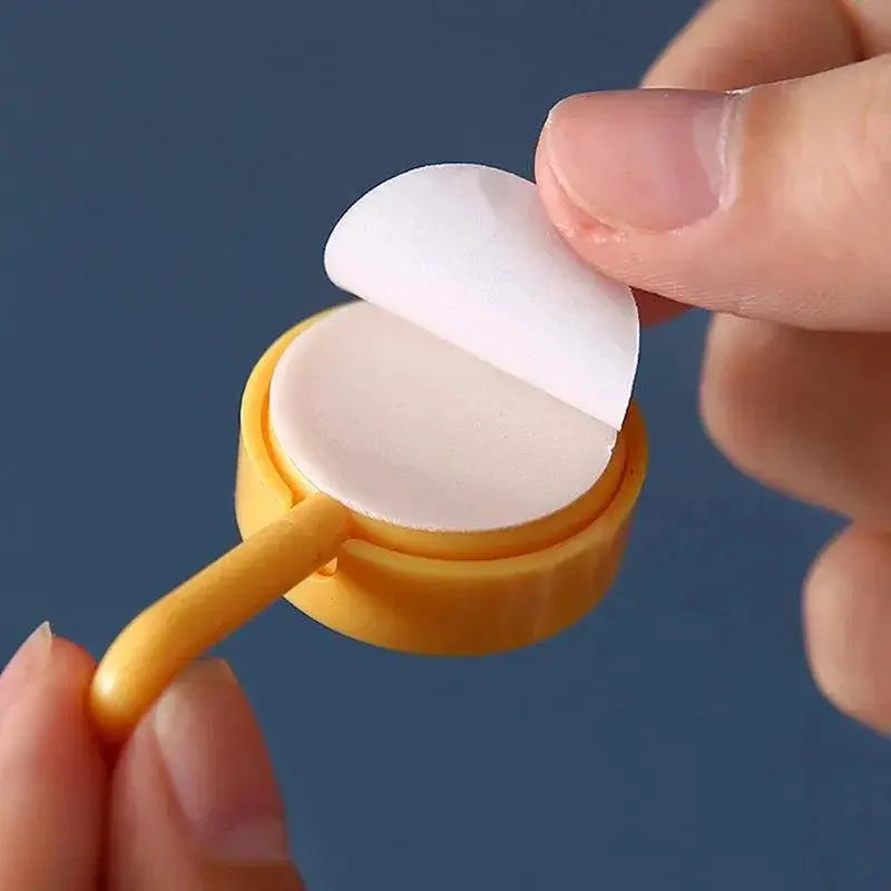 Hand peeling adhesive backing from yellow decorative wall hook for kitchen or bathroom