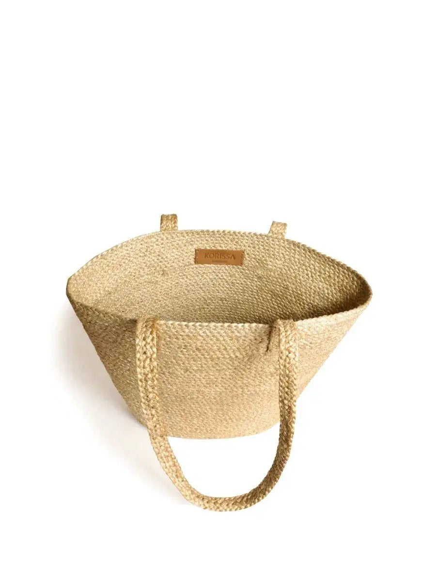 Natural woven shoulder bag with handles and leather KORISSA label on white background