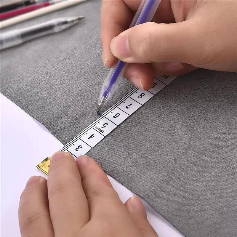 Person using heat erasable magic marker pen and measuring tape on gray fabric for sewing at OurLum.com