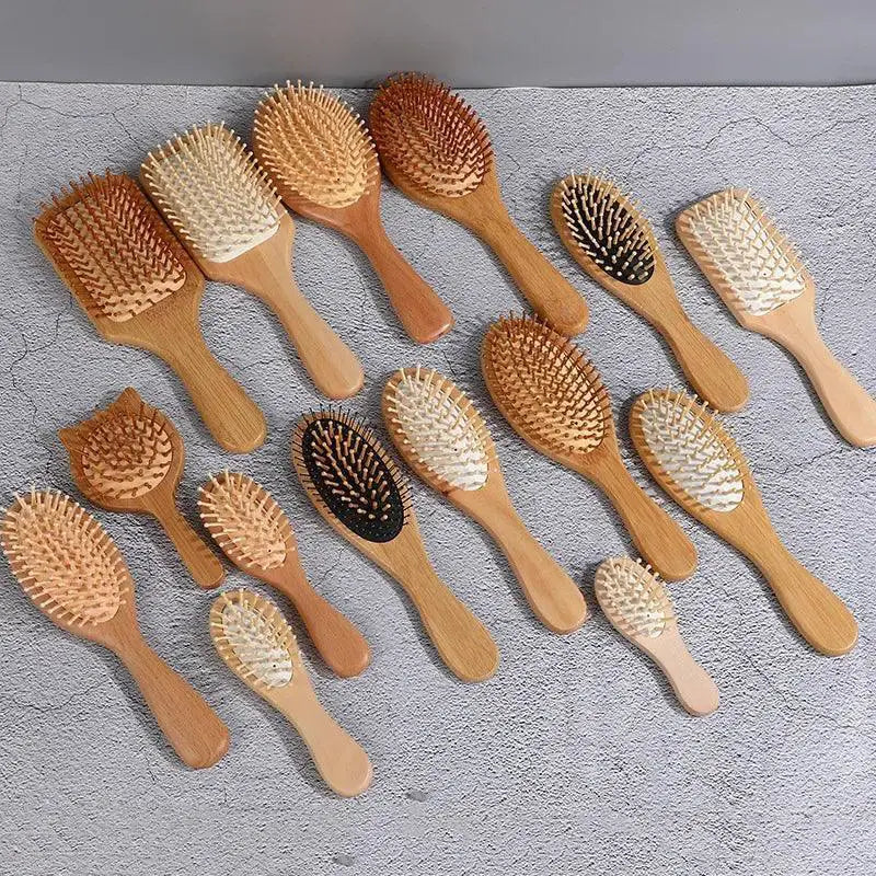 Assorted bamboo hair combs with wooden bristles on a textured gray surface.