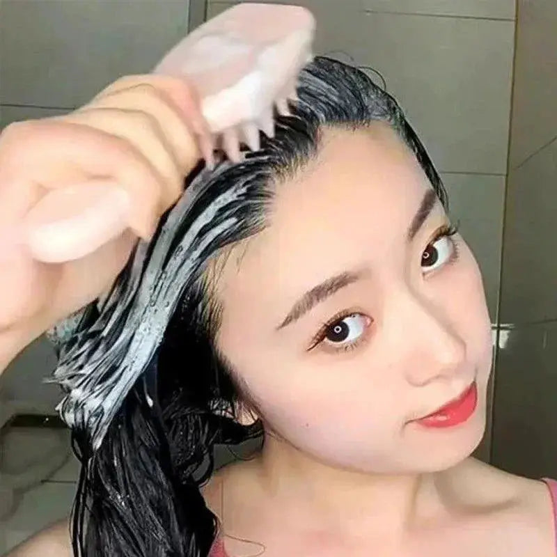 Woman using pink silicone scalp massager brush while shampooing wet hair in bathroom