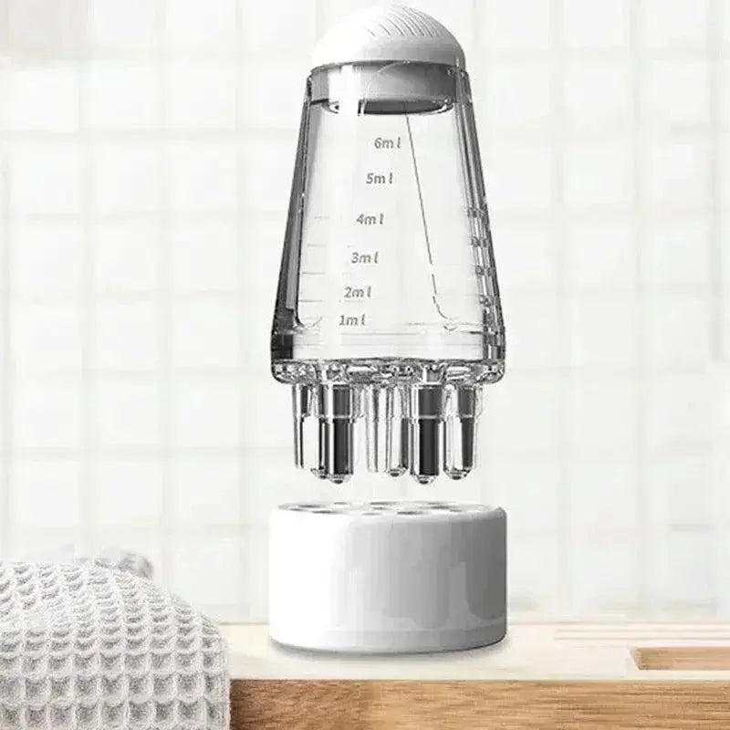 Clear scalp massager comb with liquid measurement marks and massage tips on a bathroom counter.