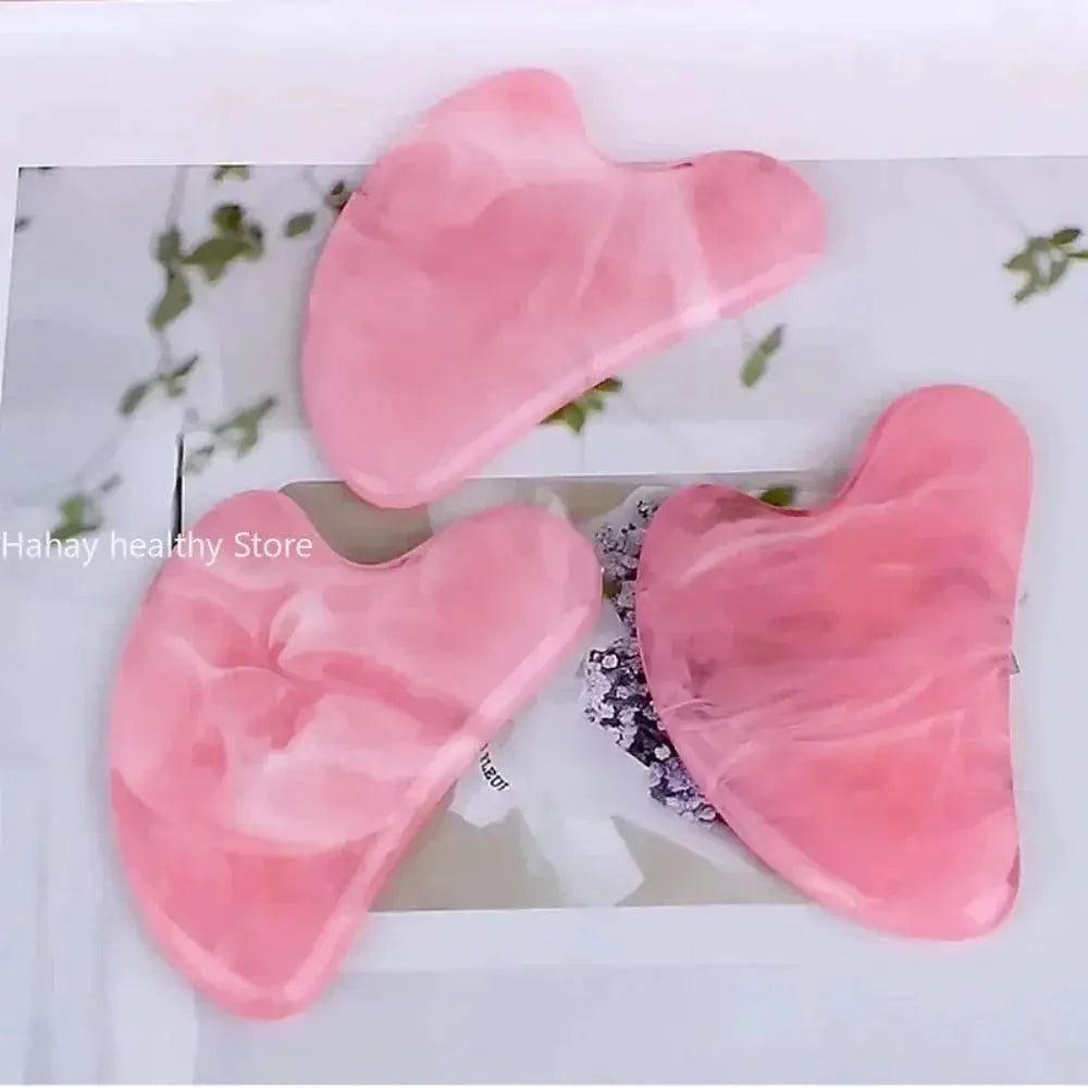 Pink jade facial gua sha massage tools on a white surface