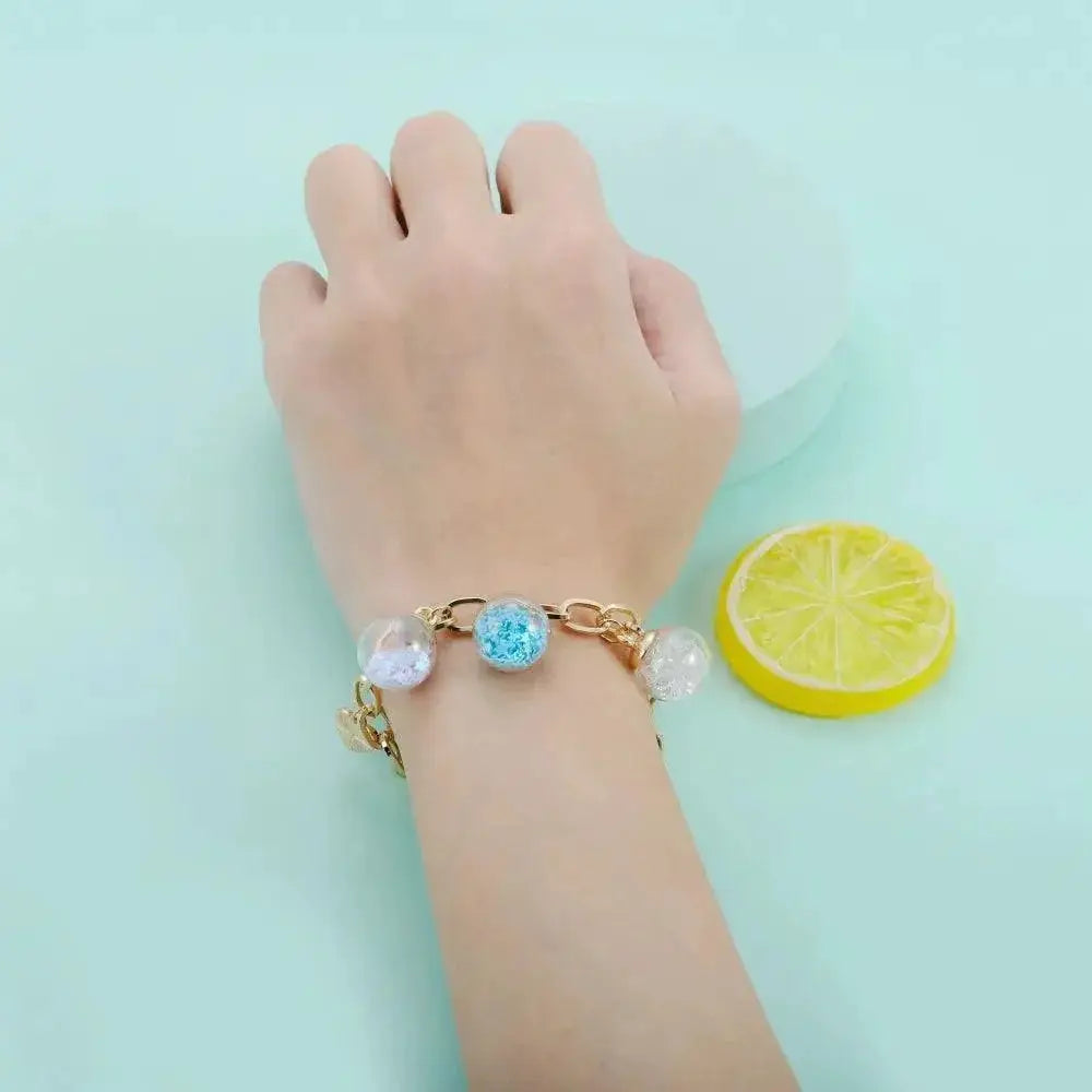 Hand wearing gold bracelet with glass ball pendants, OurLum.com handmade jewelry product