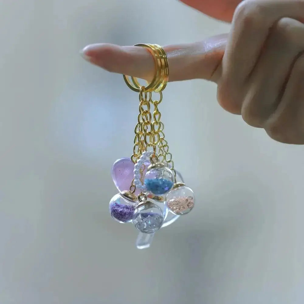 Hand holding gold chains with transparent glass ball pendants filled with colorful sequins