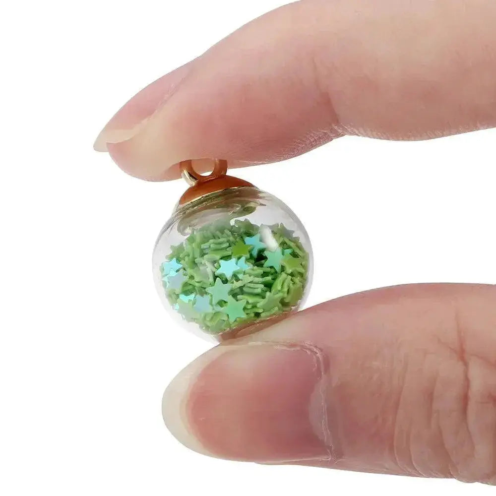 Hand holding a transparent glass ball pendant with green star sequins, jewelry DIY OurLum.com