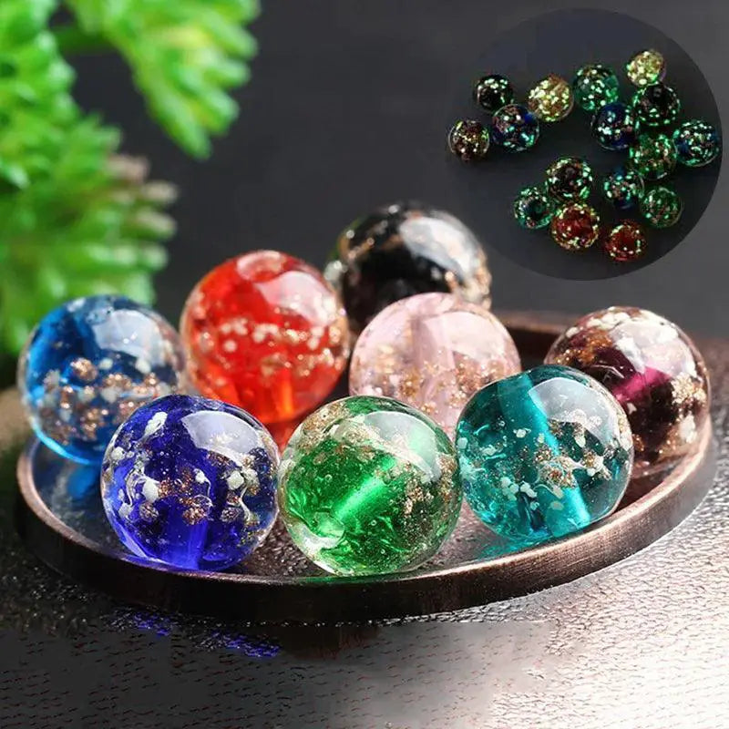 Colorful handmade luminous glass beads with gold flakes on a tray for jewelry making