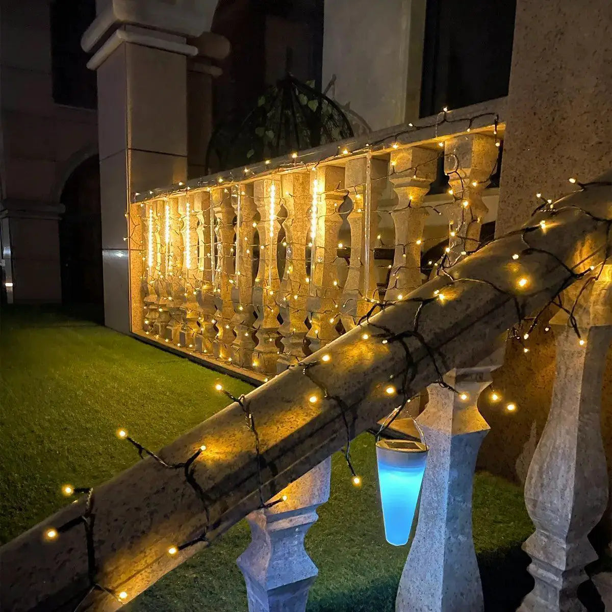 Warm LED string fairy lights decorating an outdoor stone railing at night, garden party lighting
